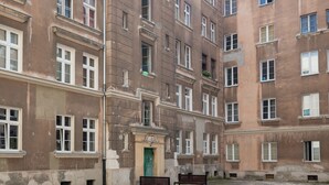 A multi-story building with a central courtyard, featuring a green door, a bench, and a small fountain. - Metro Wileński Varsovia Studio #2 (Warszawa)