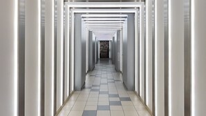 A modern, well-lit hallway with a checkered floor and a series of doors on either side. - Rondo ONZ City View Apartment (Warszawa)