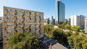 A high-rise residential building with multiple balconies and a modern skyscraper in the background. - Rondo ONZ City View Apartment (Warszawa)