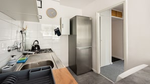 A modern kitchen with a stainless steel refrigerator, a sink with a dish rack, and a wooden countertop. - Rondo ONZ City View Apartment (Warszawa)