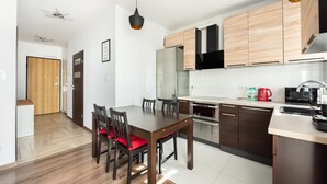 Une cuisine moderne avec des meubles en bois, une table à manger avec des chaises et un four encastré.