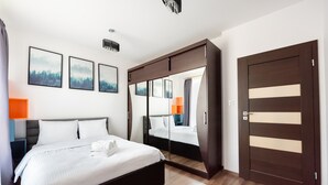 Une chambre d’hôtel moderne avec un grand lit, une armoire avec un miroir et des tableaux encadrés au mur.