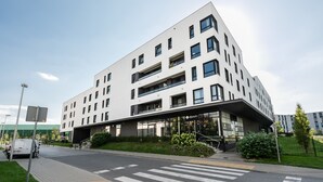 Un immeuble moderne à plusieurs étages, doté d’un toit plat, de grandes fenêtres et d’une entrée abritée.