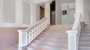 A grand staircase with white balustrades, a modern light fixture, and a tiled floor.