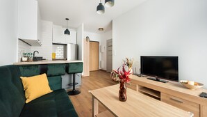 Een moderne woonkamer met een groene bank, een houten salontafel en een flatscreen televisie.