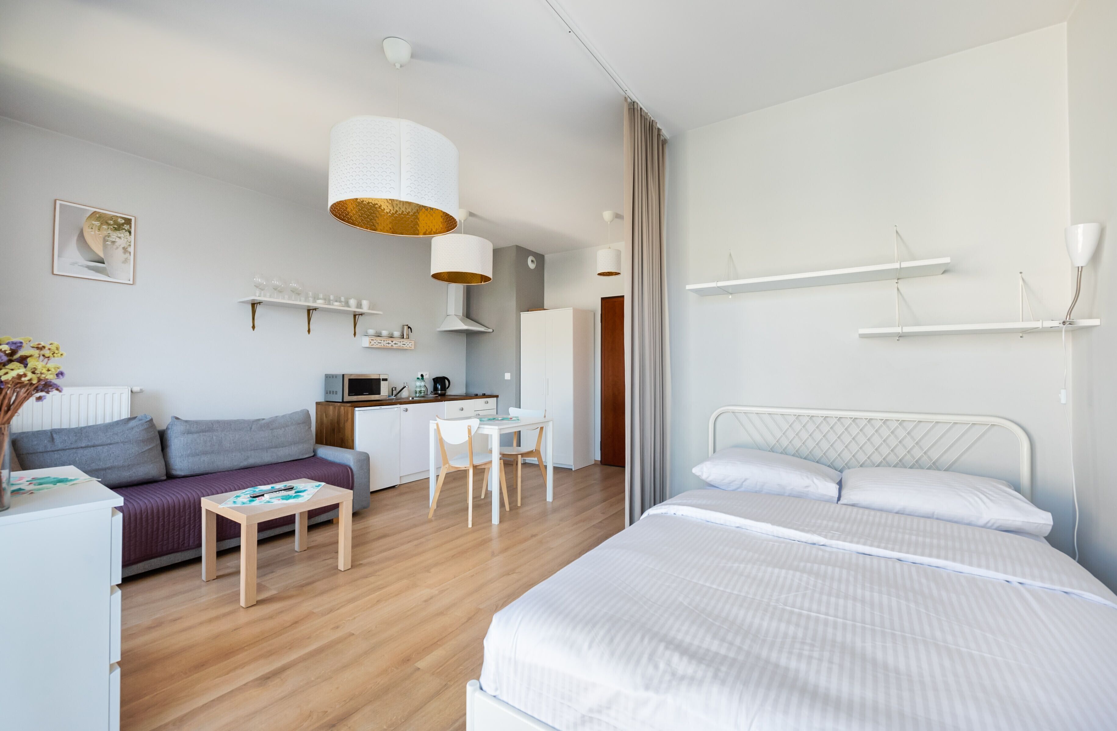 Una camera d'albergo moderna con un letto, un divano, un tavolo da pranzo e un angolo cottura.