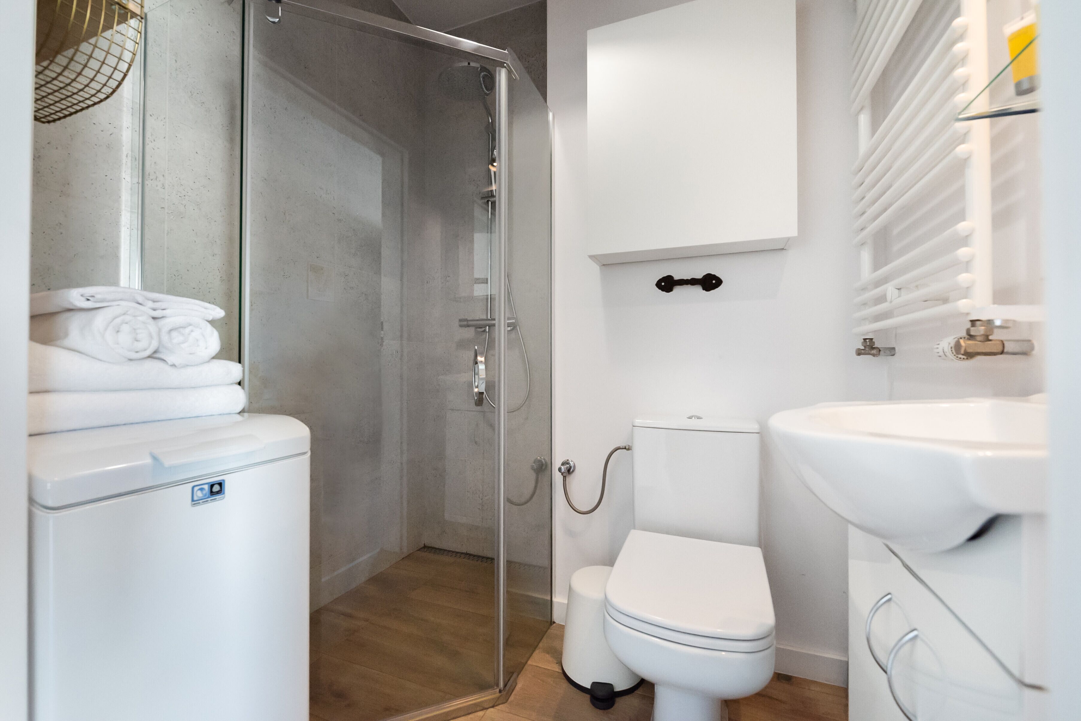 A modern bathroom with a glass-enclosed shower, a white toilet, and a sink.