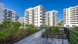 A modern apartment complex with multiple high-rise buildings, a paved walkway, and landscaped areas. - Lotnisko Chopina Modern Studio (Warszawa)