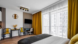 A hotel room with a large bed, a desk with two chairs, a TV, and a window with curtains. - Lotnisko Chopina Modern Studio (Warszawa)