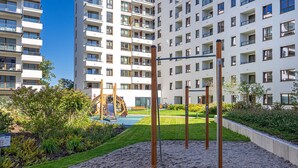 A playground with a slide and climbing structure, surrounded by a landscaped garden with a gravel path. - Lotnisko Chopina Modern Studio (Warszawa)