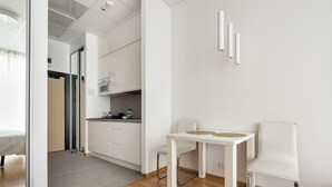 Une cuisine moderne avec des meubles blancs, une table à manger avec deux chaises et des luminaires suspendus.