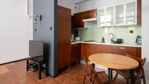 Une cuisine moderne avec des meubles en bois, un four encastré et un coin repas comprenant une table ronde et des chaises.