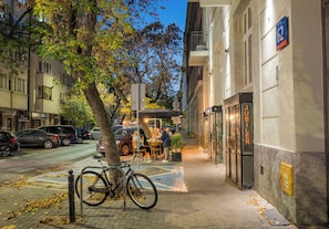 A street view with parked cars, a bicycle, and a sidewalk cafe. - Hoża 62 Comfort Studio (Warszawa)