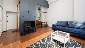 Un salon moderne avec un canapé bleu, un téléviseur, une table basse et un tapis à motifs.