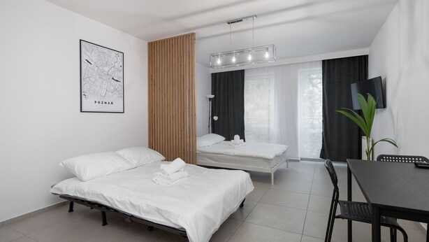 Une chambre d’hôtel moderne équipée de deux lits simples, d’une table à manger, d’un téléviseur et d’une carte affichée au mur.