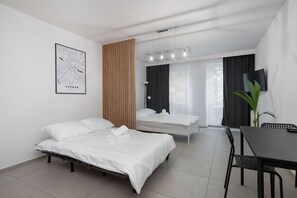 A modern hotel room with two single beds, a dining table, a TV, and a map on the wall. - Stary Browar Studio #31 FREE PARKING (Poznań)
