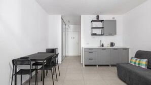 Un espace de vie compact comprenant un coin cuisine, un coin repas et un canapé.