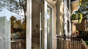 A balcony with a glass door leading to a living area, a small table, and a sofa. - Saska Kępa Loft Style Apartment (Warszawa)