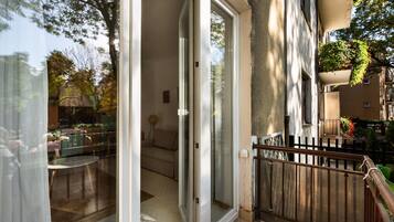 Un balcon avec une porte-fenêtre donnant sur un espace de vie, une petite table et un canapé.