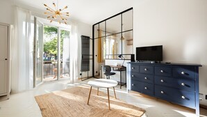 A modern living room with a large window, a white sofa, a black TV stand, and a desk with a chair. - Saska Kępa Loft Style Apartment (Warszawa)