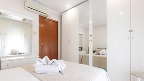 A neatly arranged bedroom with a bed, a bedside table, a mirror, and a wardrobe. - Charming House in Roses, Costa Brava: Private Pool, Close to the Beach, Ideal for Families and Groups. (Roses)