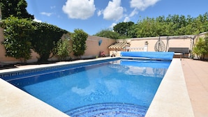 A rectangular swimming pool with a tiled edge and a blue cover. - Charming House in Roses, Costa Brava: Private Pool, Close to the Beach, Ideal for Families and Groups. (Roses)