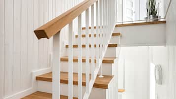 A staircase with wooden steps and white railings, leading to a landing with a potted plant.