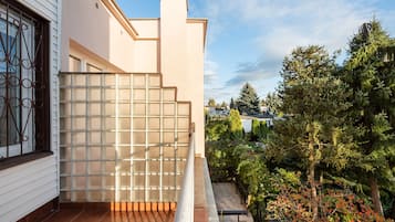 Ein Balkon mit Blick auf einen Garten und angrenzende Häuser.