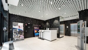 A modern lobby with a marble floor, a reception desk, and a unique ceiling design. - New Varsovia Comfort 310 (Warszawa)