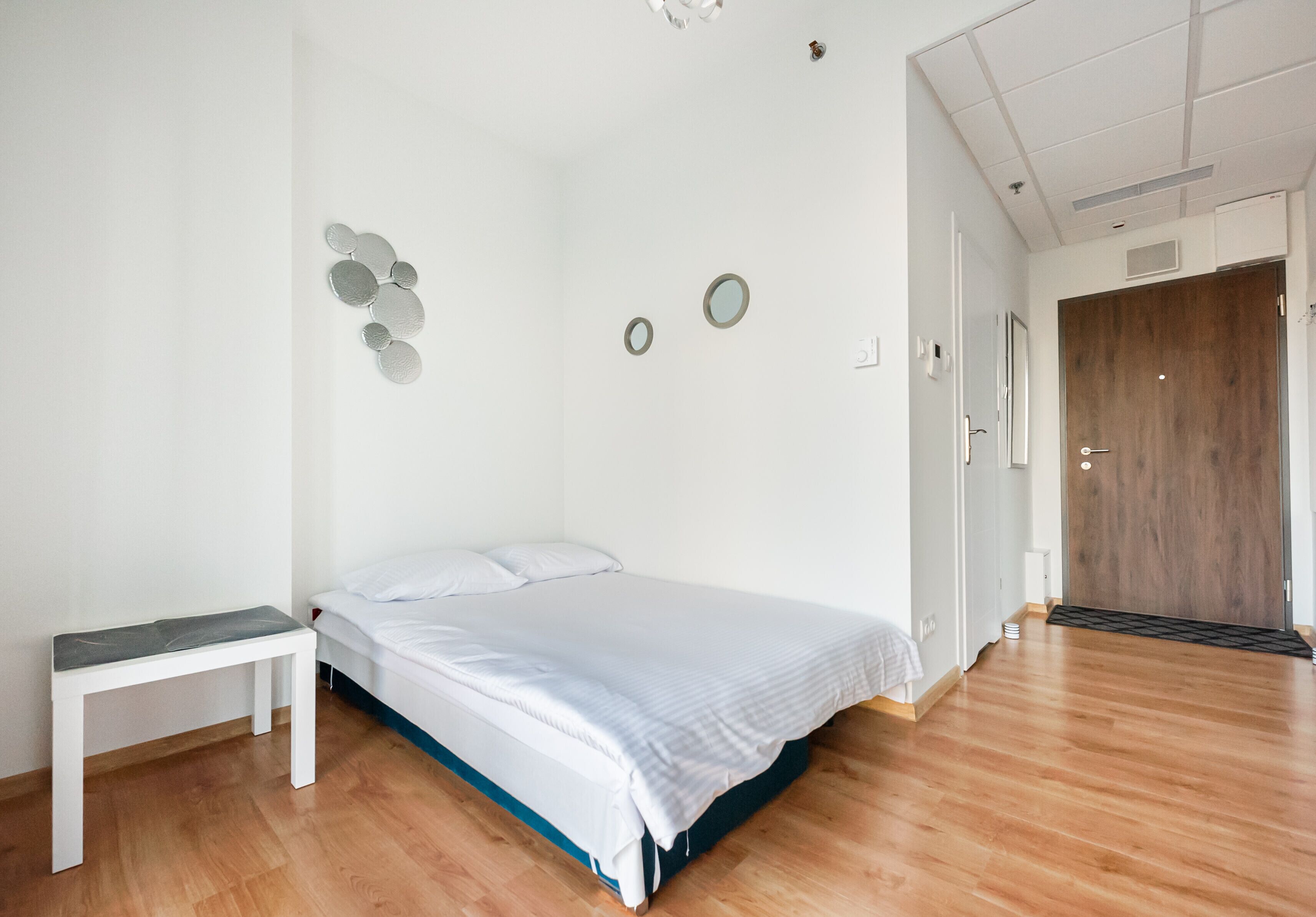Une chambre à coucher avec un lit, une table de chevet, un plancher en bois et une porte.