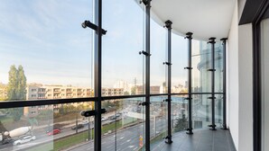 A balcony with a city view, large windows, and a tiled floor. - New Varsovia Comfort 310 (Warszawa)