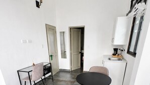 Une cuisine moderne avec un coin repas, comprenant une table ronde noire et deux chaises, un petit plan de travail avec un évier, et une vue sur la pièce adjacente.