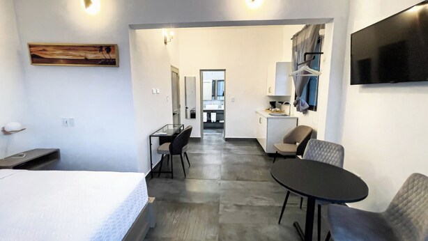 Une chambre d’hôtel moderne, équipée d’un lit, d’un bureau, d’une chaise et d’une petite table. Un téléviseur est fixé au mur, et un tableau est accroché au mur.