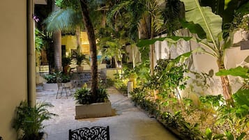 Un espace extérieur aménagé en patio, avec des sièges, des plantes en pot et un chemin en pierre.