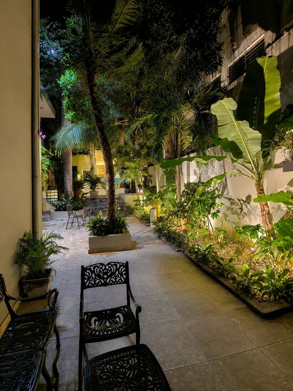 An outdoor patio area with seating, potted plants, and a stone pathway. - Hotelito Bonito Eli & Edw (Santo Domingo)