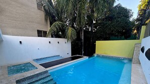 Une piscine avec des marches permettant d’y accéder, entourée de murs et de verdure.