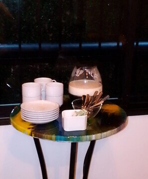 A table with stacked white plates, a glass pitcher, and a small bowl with cinnamon sticks. - Hotelito Bonito Eli & Edw (Santo Domingo)