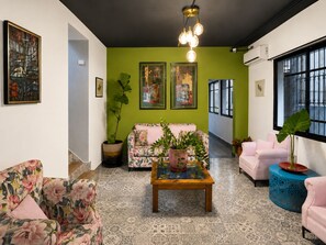 Een woonkamer met een groene accentmuur, een bank, een salontafel en een groot raam.