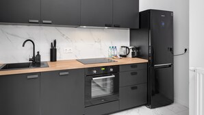 Una cocina moderna con armarios oscuros, salpicadero de mármol, refrigerador negro y horno integrado.