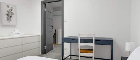Habitación de hotel moderna con cama, escritorio y silla. Hay un cuadro en la pared y una ventana con luz natural.