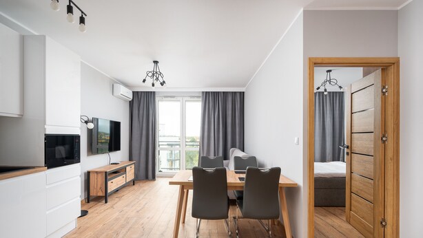 A modern apartment with a dining area, kitchen, and a bedroom. - Wiktoryn Comfortable Two-Room Apartment (Warszawa)