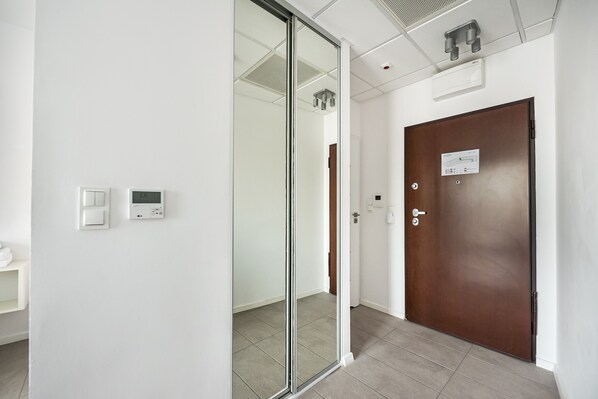 A hallway with a sliding glass door, a wooden door, and a thermostat on the wall.