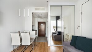 A modern hotel room with a dining area, a sofa, and a glass door leading to a balcony. - Varsovia Comfort 629 (Warszawa)