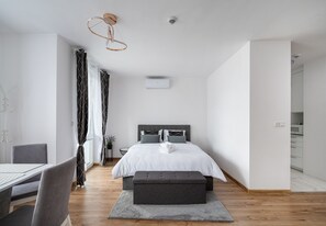 A modern bedroom with a bed, bedside tables, a desk, and a dining area. - Modern Space Glamour Studio (Warszawa)