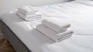 A neatly made bed with white linens and folded towels. - Służew 405A Apartment (Warszawa)
