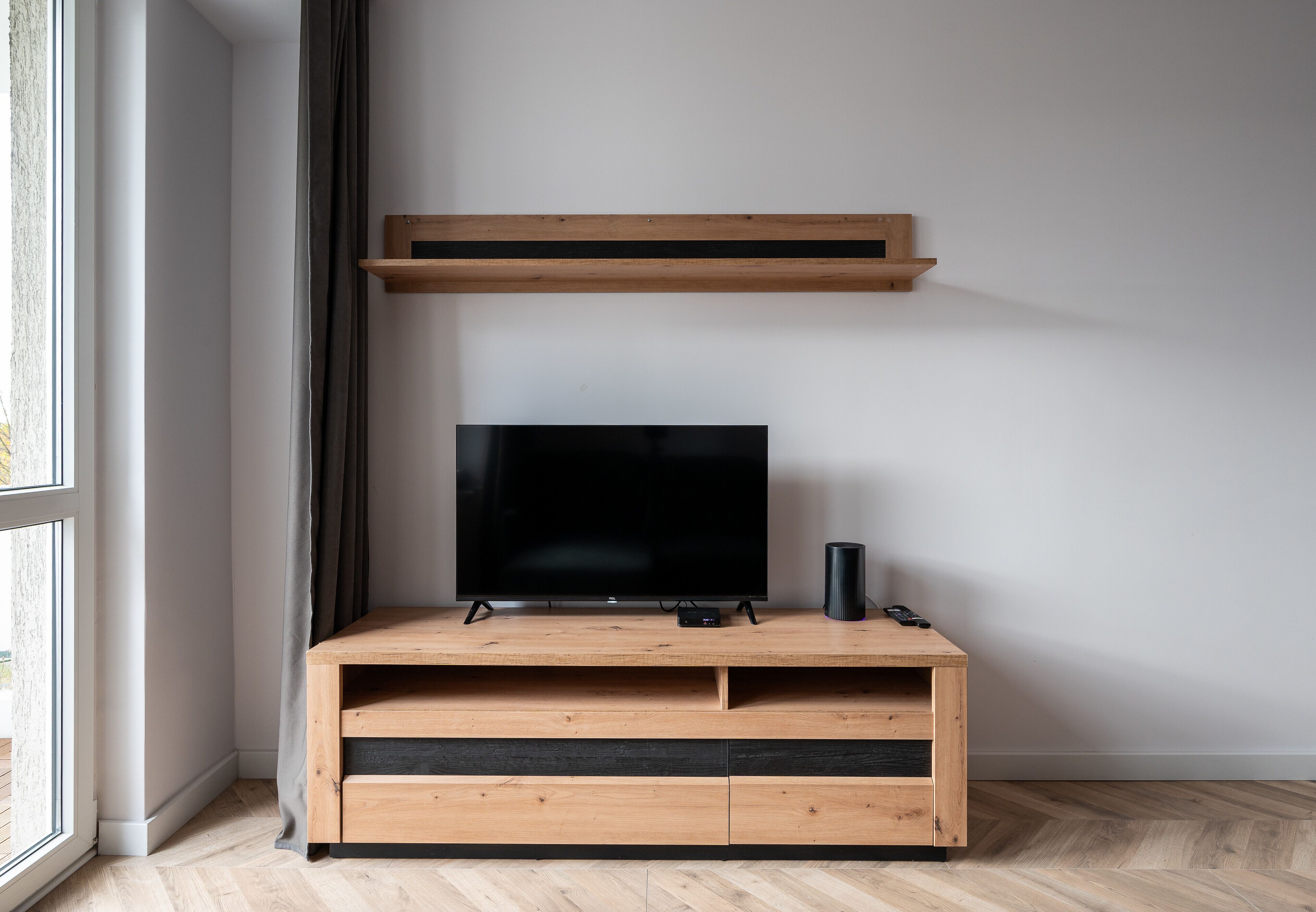 Ein modernes Wohnzimmer mit einer Holzeinbauwand, einem Flachbildfernseher und einem Lautsprecher.