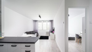Un espacio habitable moderno y minimalista con cocina, una mesa de comedor y un dormitorio.