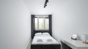 Un dormitorio moderno con cama, escritorio y silla.