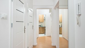 A hallway with white doors and wooden flooring leading to a kitchen area. - Old Town 5-Bedroom Apartment (Warszawa)
