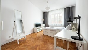 A modern bedroom with a bed, a desk, a mirror, and a TV. - Old Town 5-Bedroom Apartment (Warszawa)